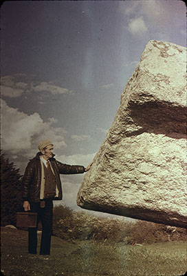 man pressing on large rock